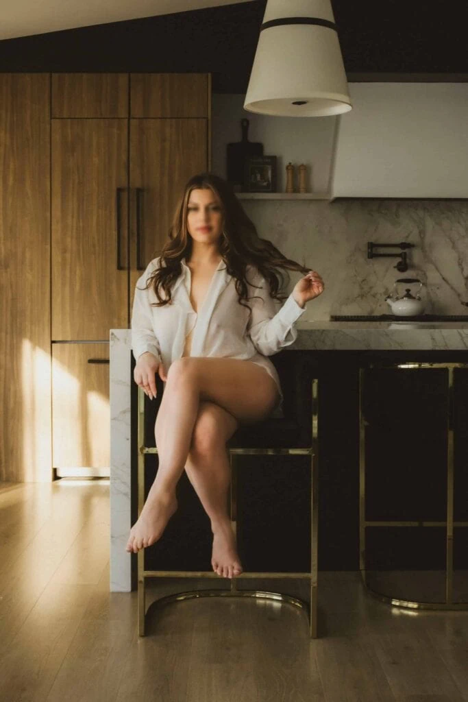 Ava Marie sits elegantly on a stool in a stylish kitchen, bathed in warm, natural light. Ava Marie Halifax's Elite Independent Companion